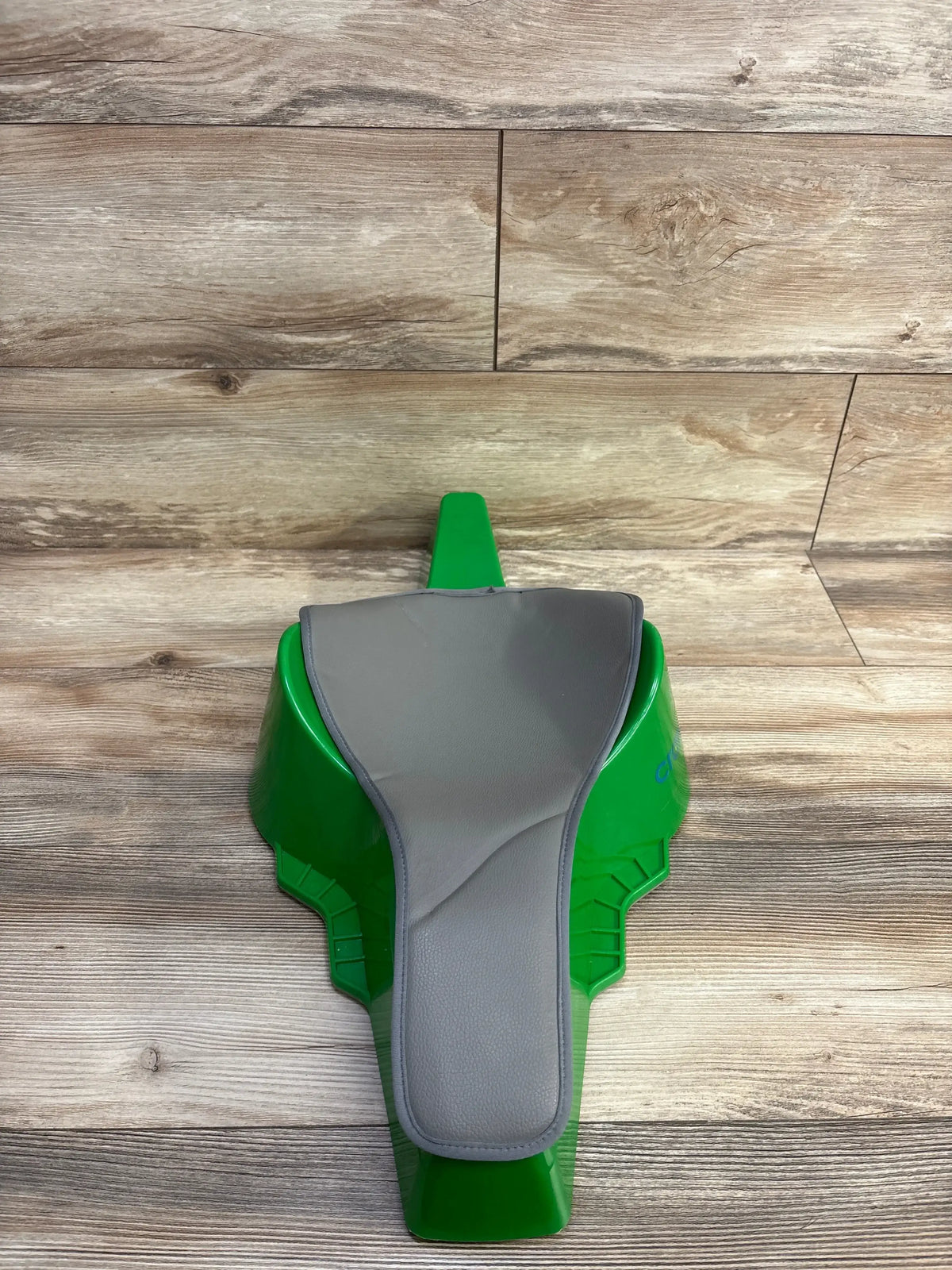 Top-down view of Crawligator Tummy Time Toy in green showing gray cushioned tummy pad on wood floor background