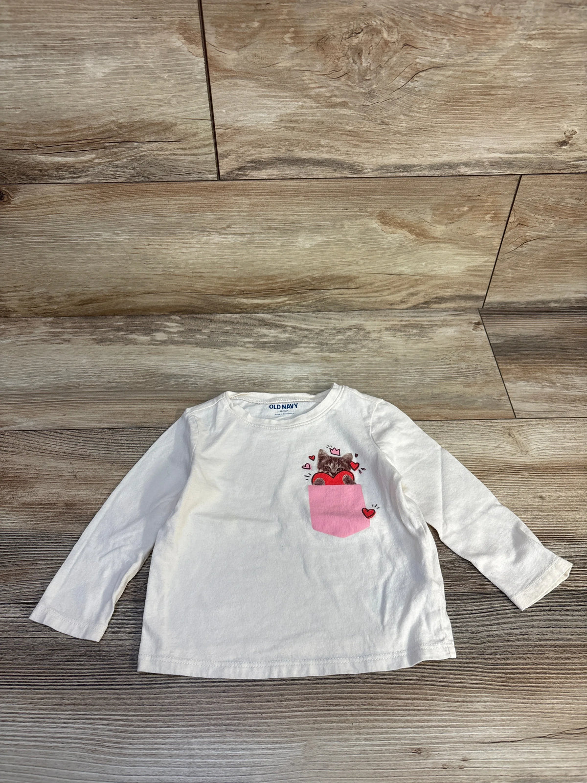 White long-sleeve toddler shirt with cat in pink pocket design, perfect for kids' clothing resale.