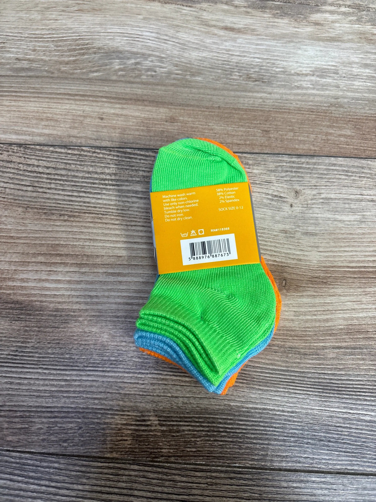 Top view of NEW Focus Solid Socks three pack for 0 to 12 months showcasing green, orange, and blue socks on wooden floor