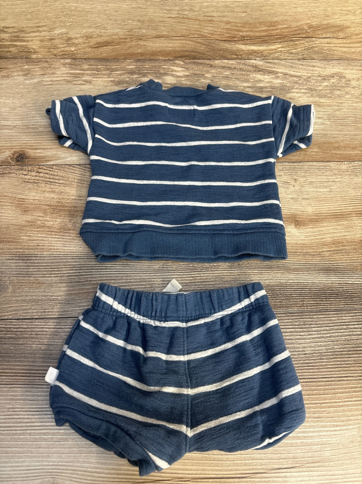 Navy blue baby outfit with white stripes, short sleeve top and matching shorts on wood background