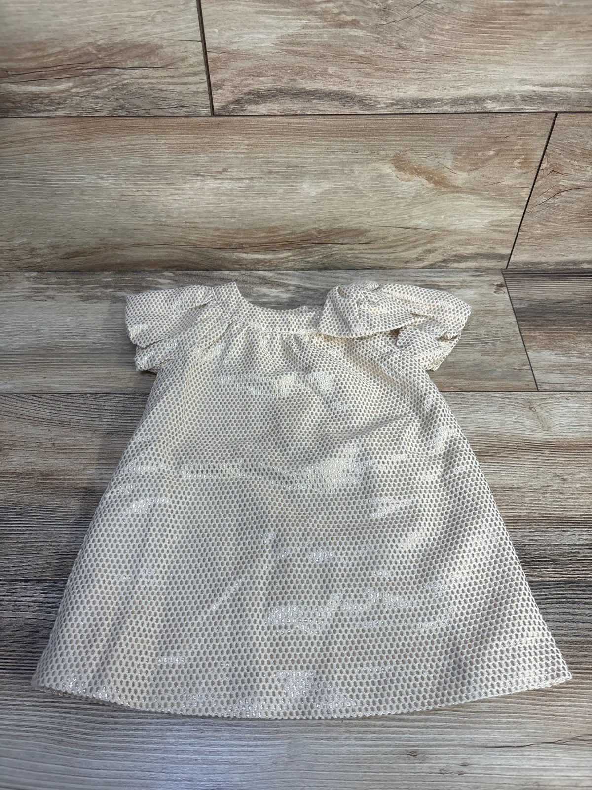Front view of Janie & Jack gold metallic jacquard dress showcasing puff sleeves and shoulder bow on wood-look floor