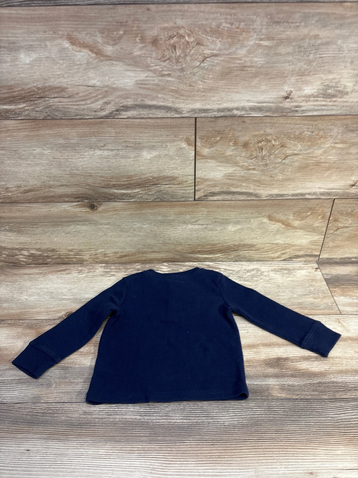 Flat-lay back view of Children’s Place navy thermal henley shirt showing long sleeves and ribbed texture on wood background