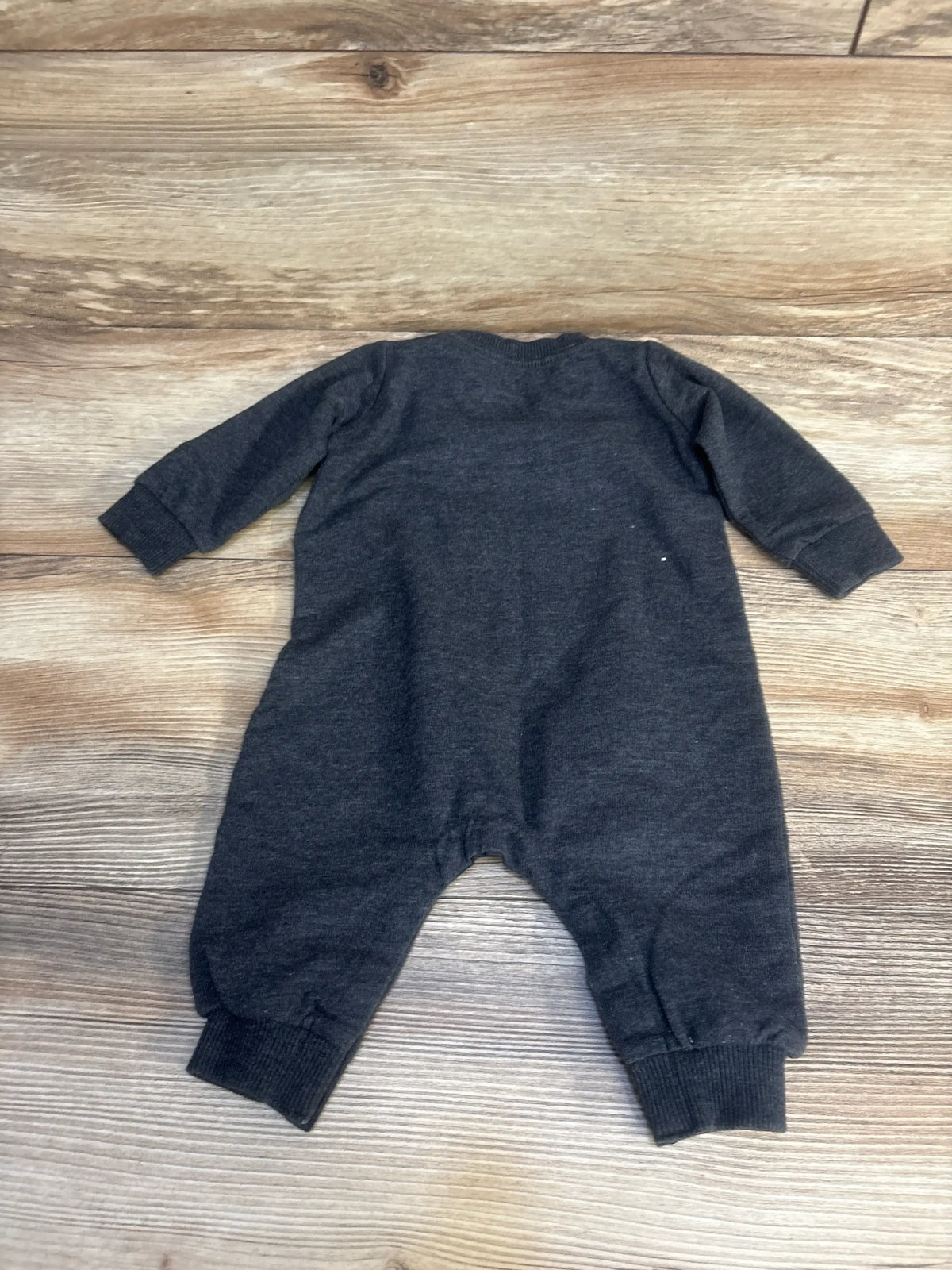 Back view of grey Nike coverall in 3-month size showing long sleeves and ribbed ankle cuffs laid flat on wood floor