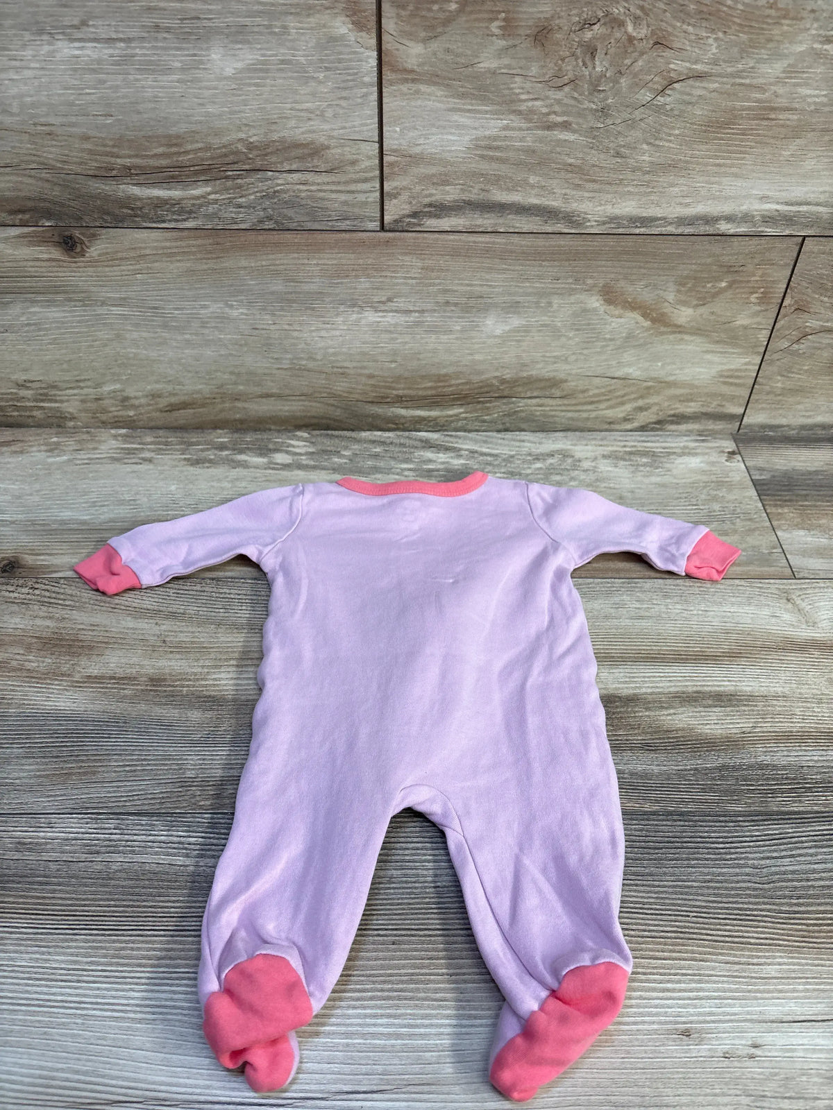 Front view of Koala Baby sleeper showcasing long sleeves, pink cuffs, and footed legs on a wood-patterned background