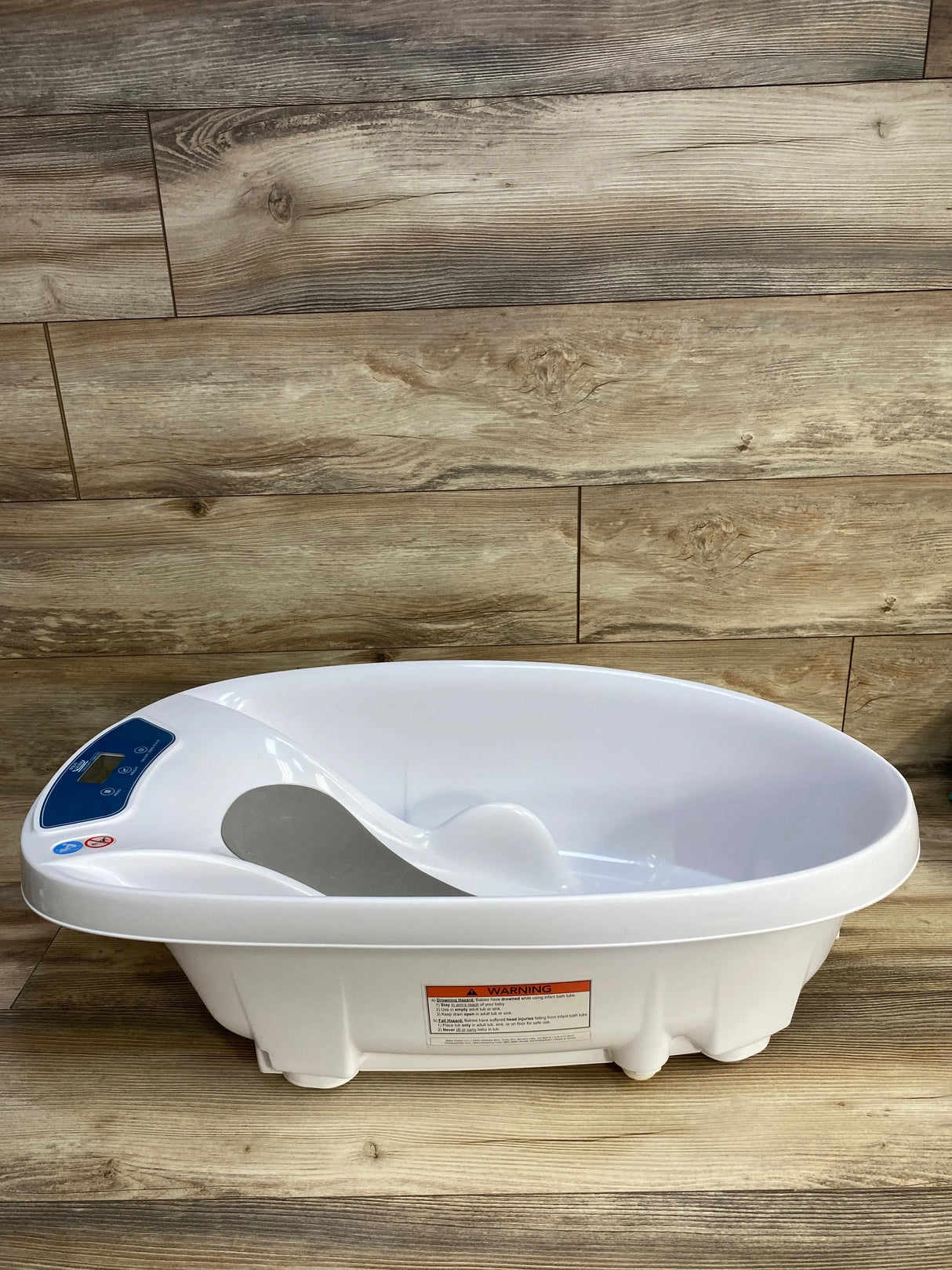 Front view of AquaScale 3-in-1 infant tub showing digital scale display and contoured baby support on wood plank background
