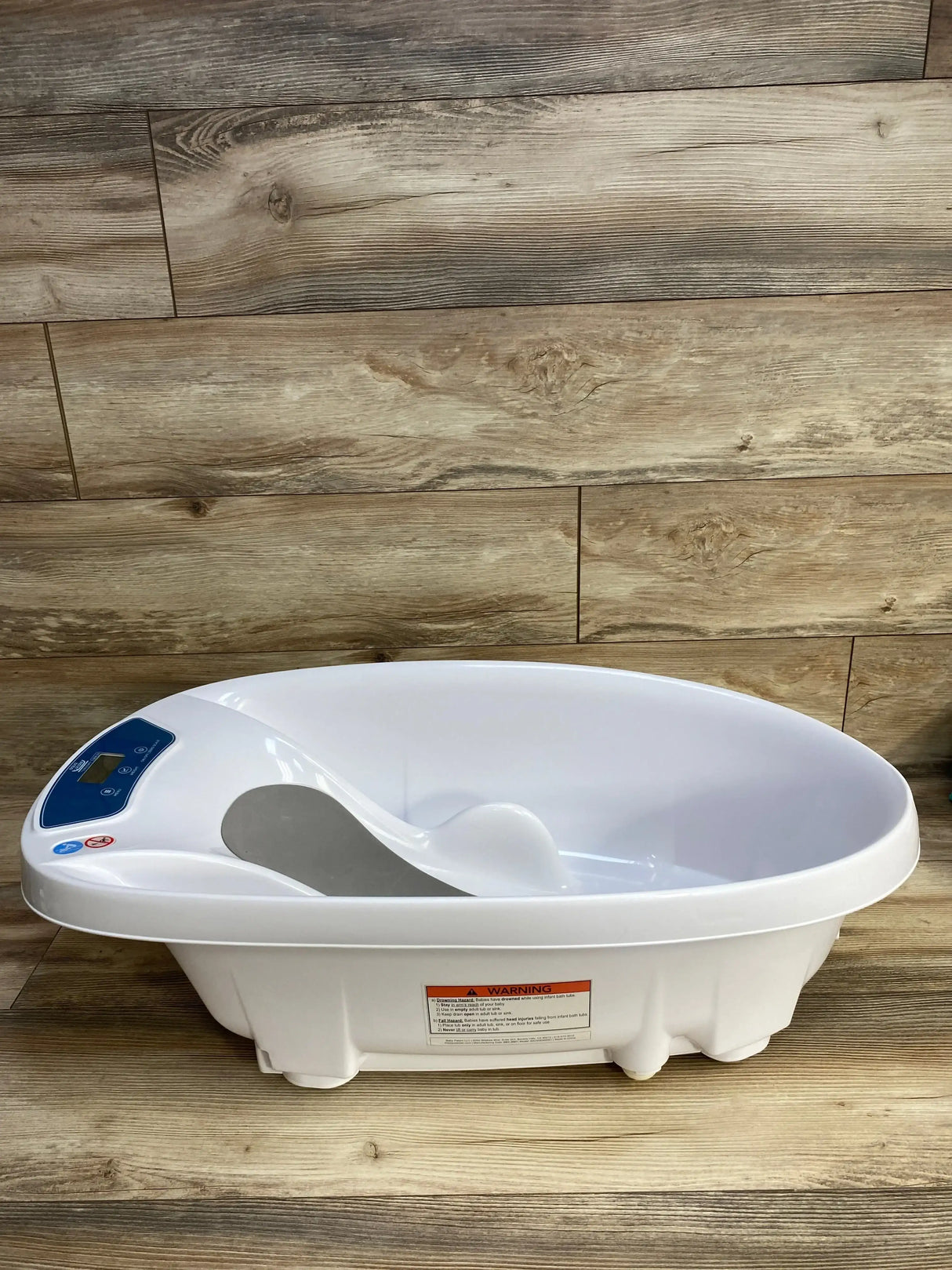 Front view of AquaScale 3-in-1 infant tub showing digital scale display and contoured baby support on wood plank background