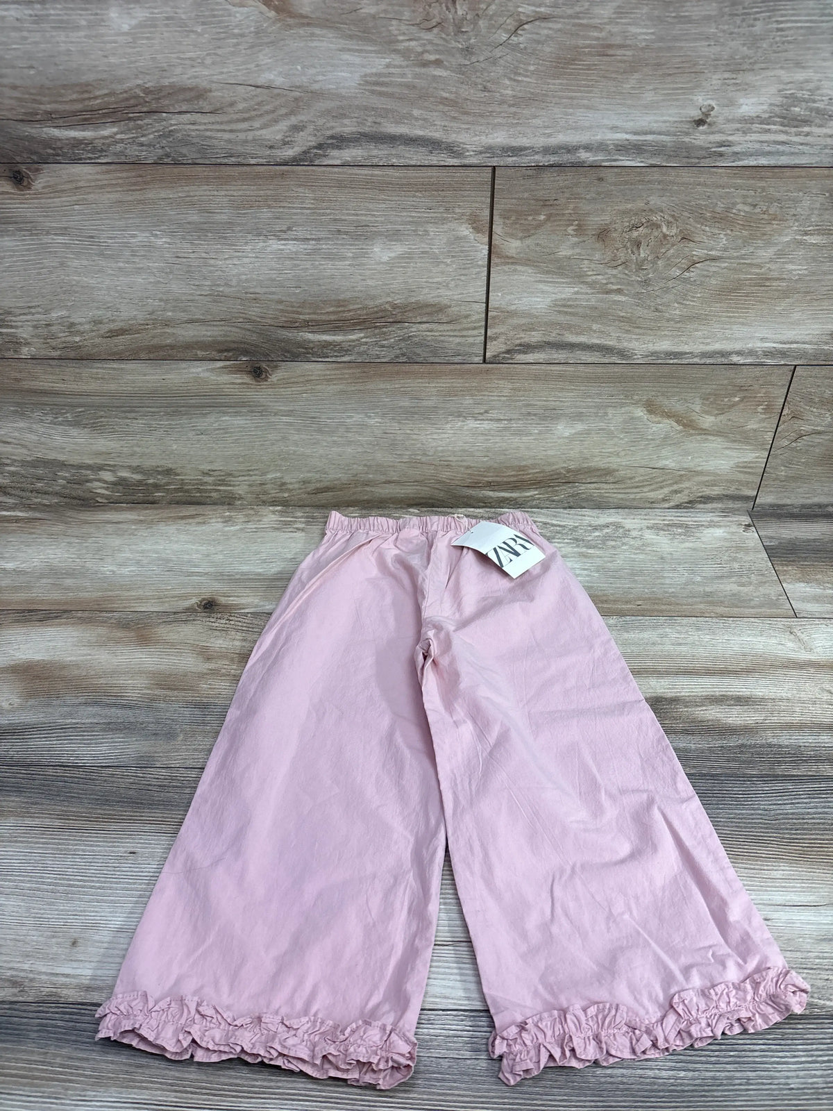 New pink Zara ruffle trim pants for size 5T laid on a wooden background