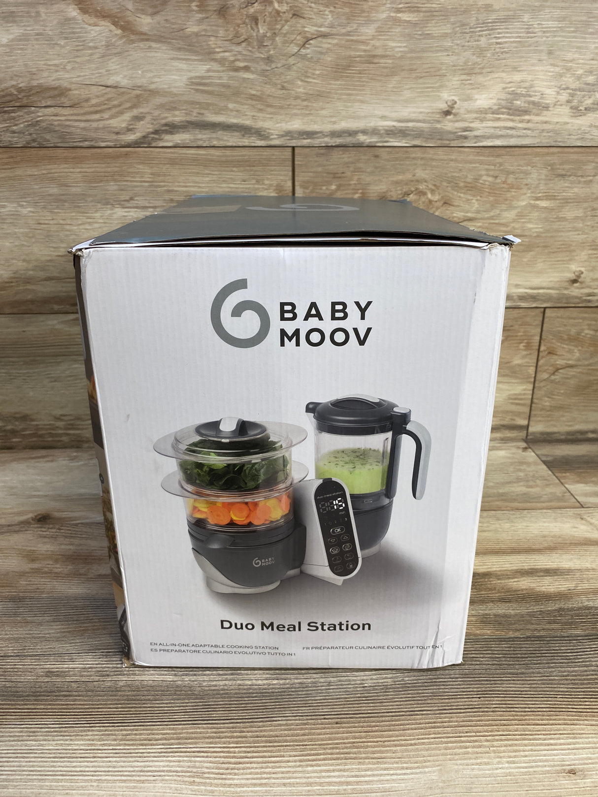 Babymoov Duo Meal Station baby food maker in box on wood floor, front product view