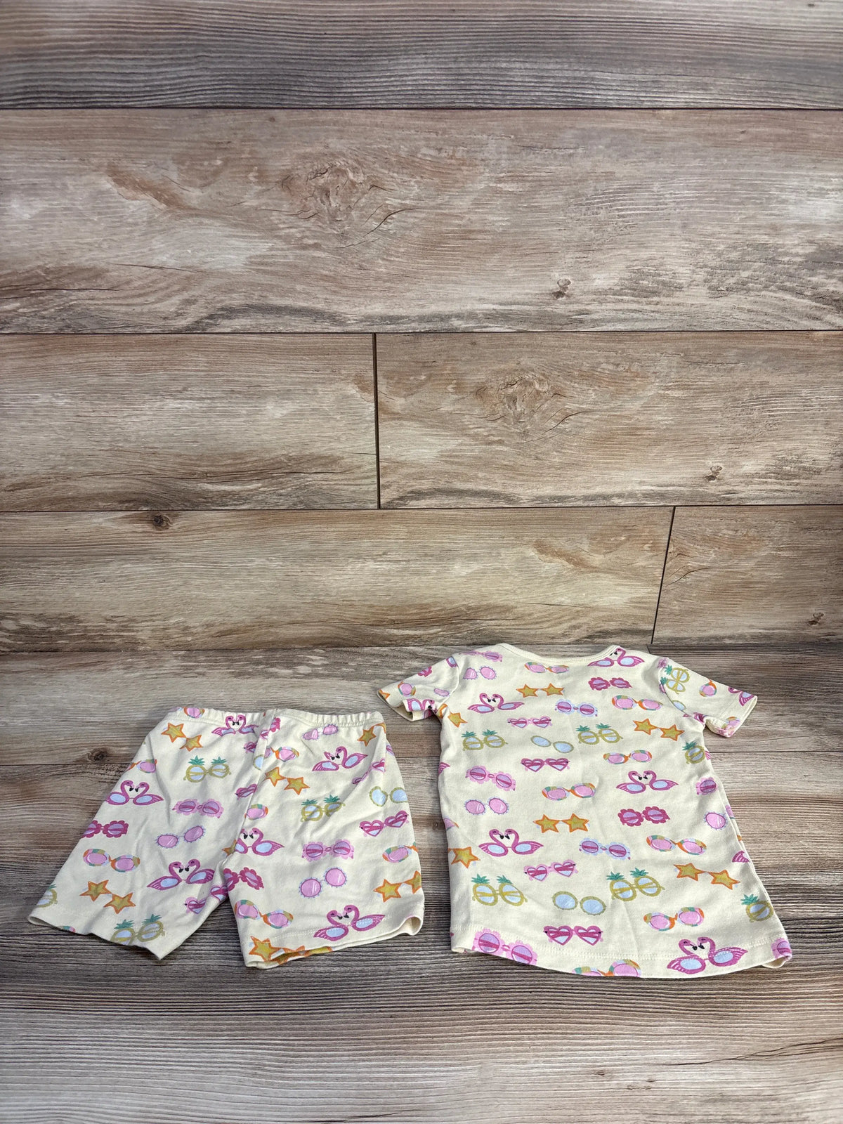 Top view of Janie & Jack 2pc short pajama set showcasing sunglass stars print on a wood-grain background