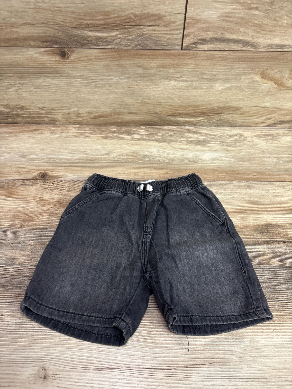 Front view of Zara drawstring denim shorts in grey, size 5T, showcasing elastic waist and side pockets on a wood floor