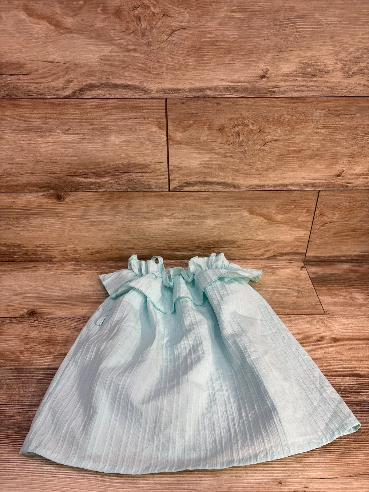 Front view of Shein blue ruffle dress, size 12 to 18 months, showing ruffled neckline and sleeves on a wood floor