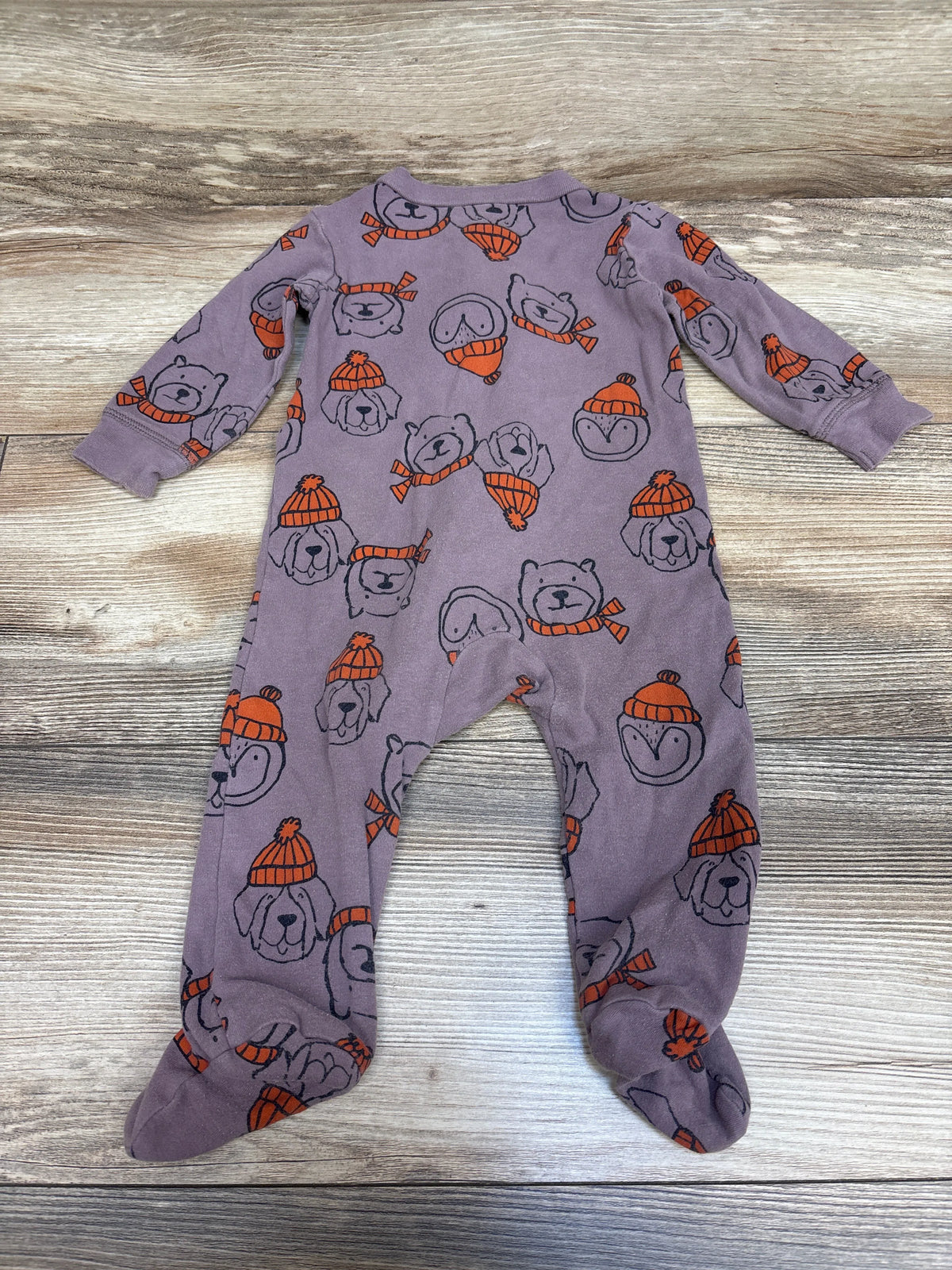Flat view of Carter’s mauve footed sleeper in size 9 months showing long sleeves and dog and beanie print on a wood grain background