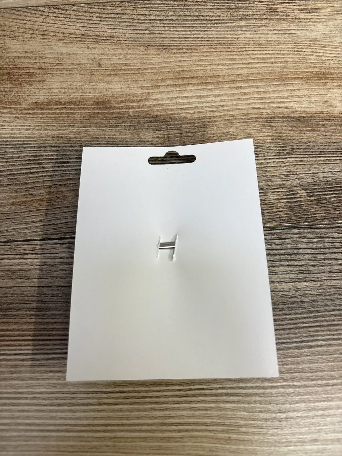 Blank white retail tag with hang hole on wood surface, ready for kids or maternity item labeling