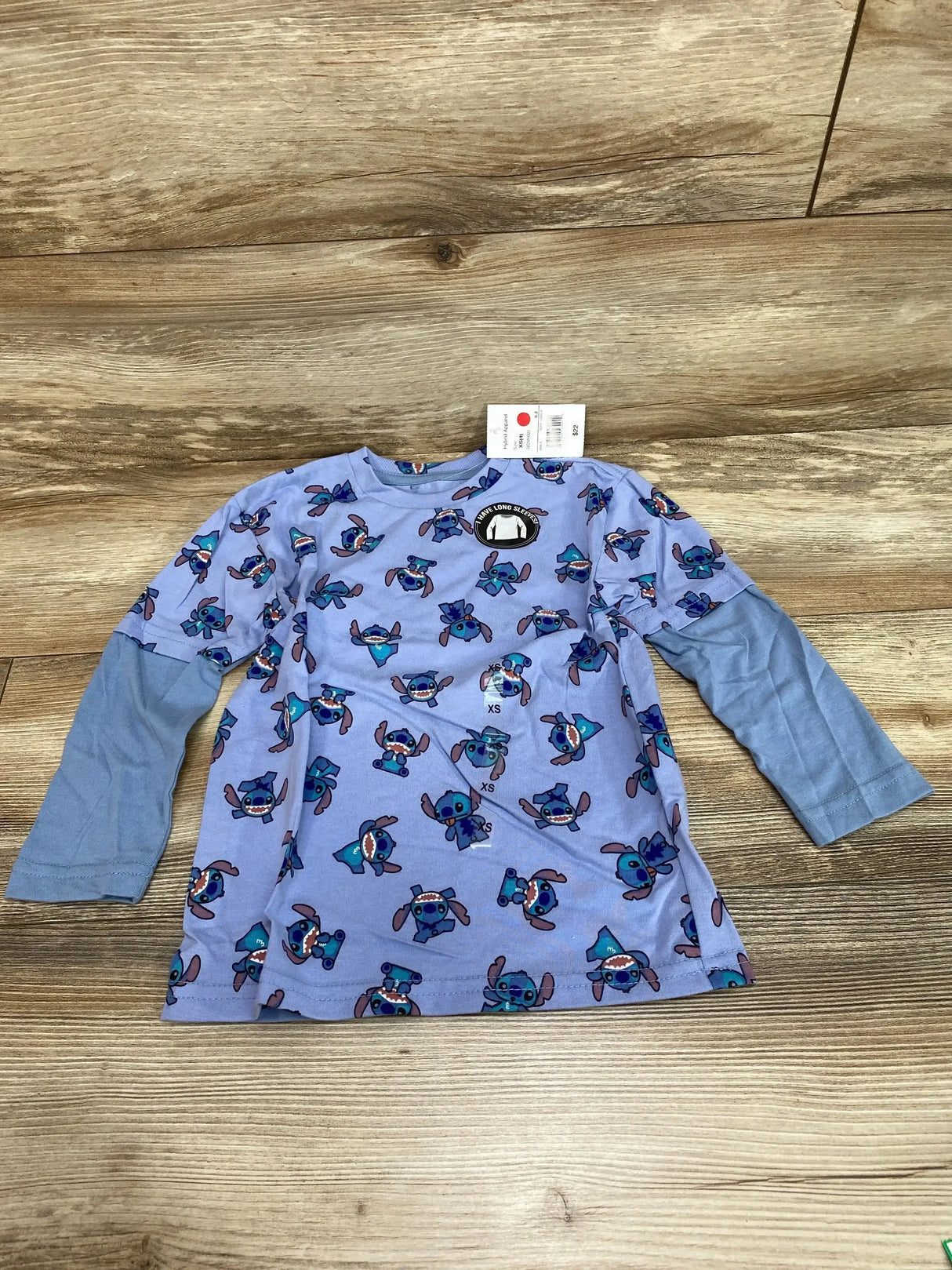 Front view of size 4T twofer Stitch long-sleeve shirt with all-over Stitch print and attached light-blue mock-layered sleeves on wood
