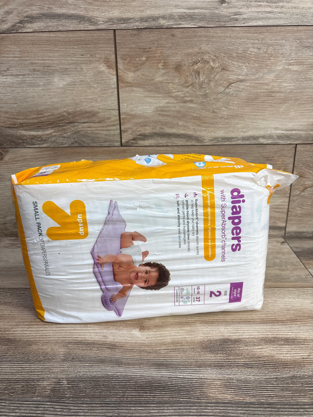 Package of up&up brand small size 2 baby diapers with SuperAbsorb channels and baby image on wood background