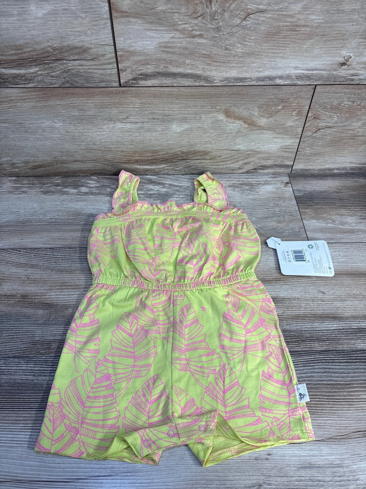 Front view of Burt’s Bees Baby lime tank shortie romper showcasing pink leaf print and snap closures on a wood-look floor