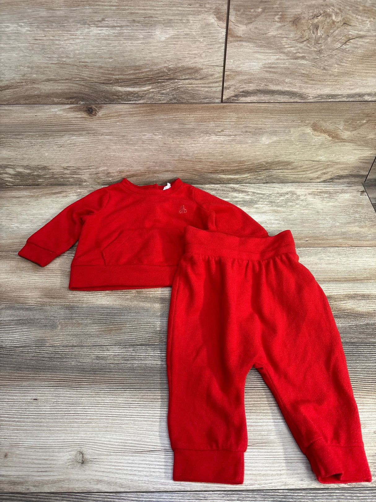Flat lay of Baby Gap 2pc Velour Pullover Sweatshirt and Joggers in red sz 3-6m showcasing soft velour fabric with logo on wood plank background