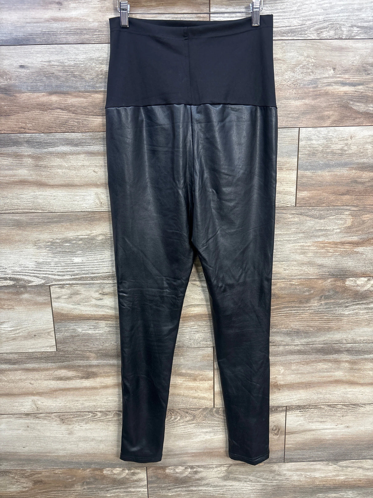 Black faux leather high-waisted leggings on wooden background