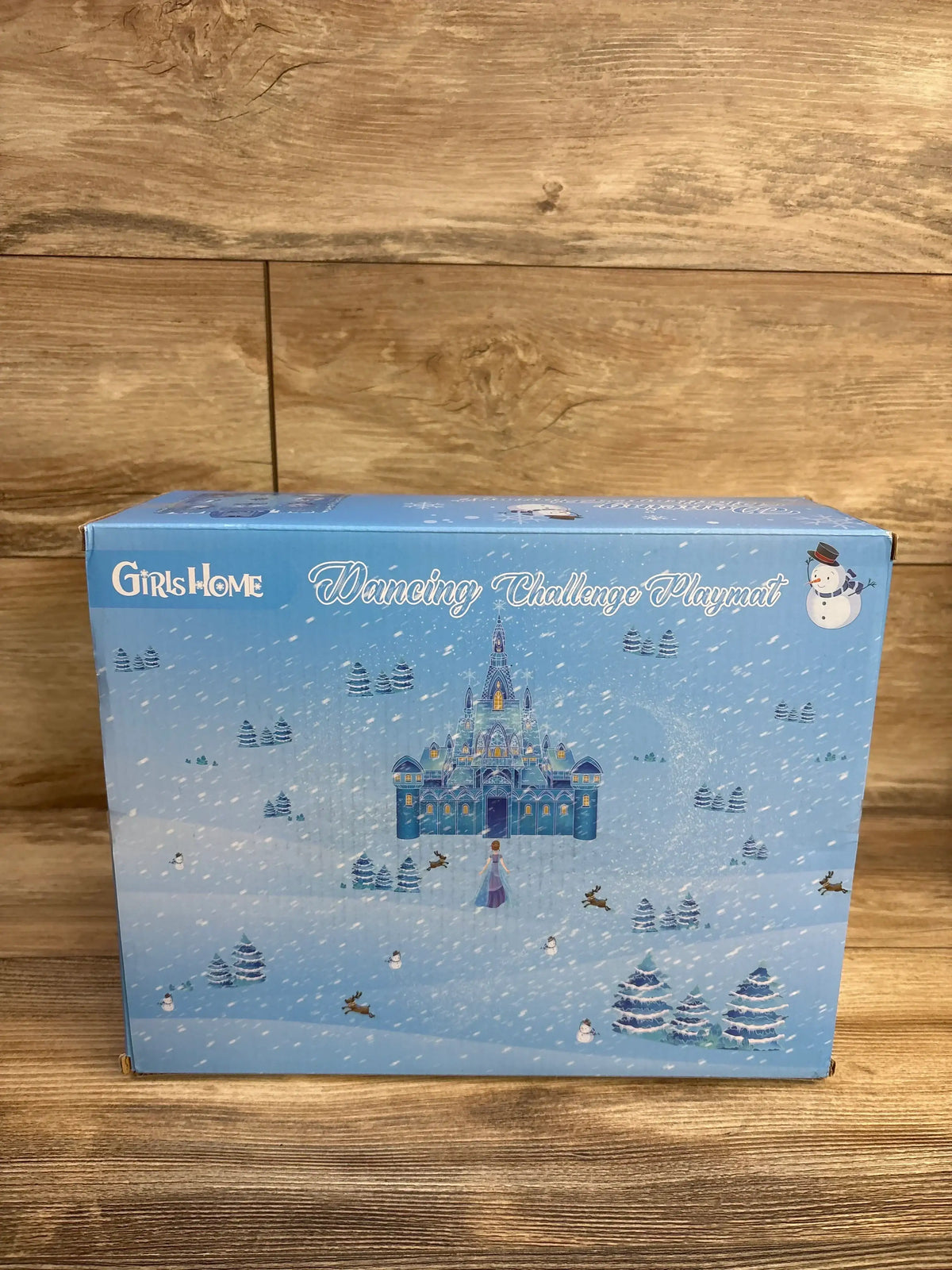 Front view of GirlsHome Frozen electronic dance mat box showcasing castle artwork and snowman graphic on wooden surface