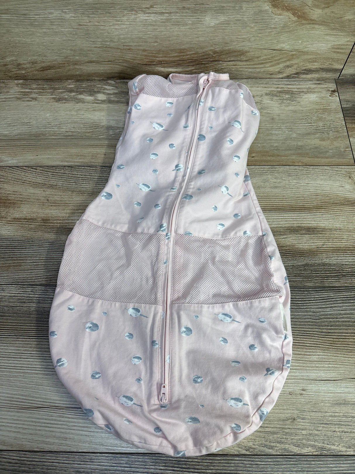 Pink baby sleep sack with white and blue planet pattern on wood floor