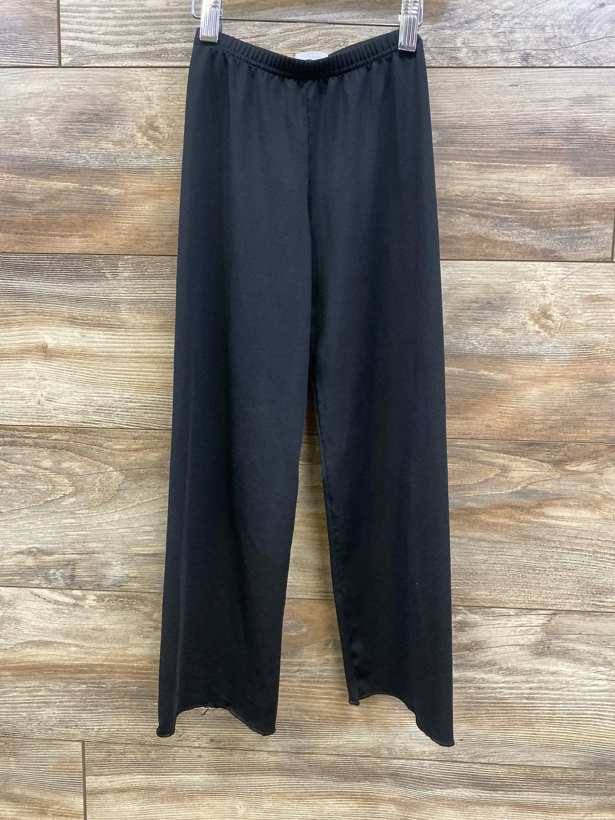 Front view of black jazz pants (toddler 4-6) showing elastic waistband and straight wide legs on wood background