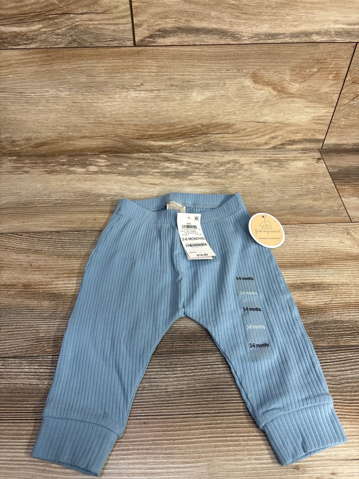 Blue ribbed baby pants for 3-6 months with tags on wooden floor, gently used kids clothes