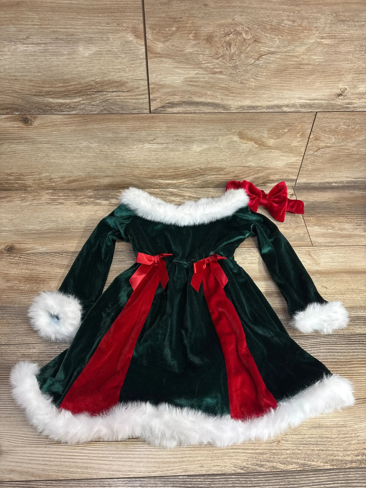 Green velvet baby Christmas dress with red ribbon, white fur trim, and matching headband for holiday photos