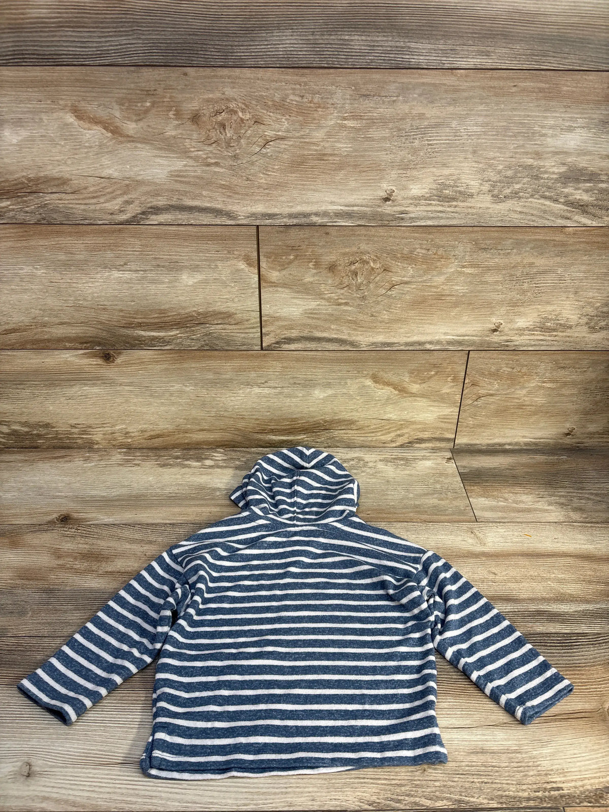 Back view of Easy Peasy hooded shirt showcasing blue and white horizontal stripes and hood against wood-look background