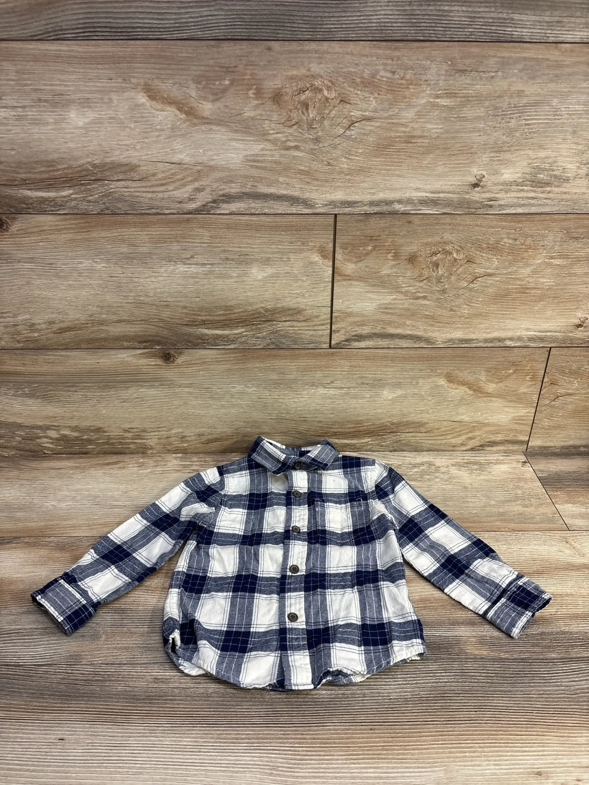 Front view of Cat & Jack toddler plaid flannel shirt showing navy and white check pattern, long sleeves, wood floor background