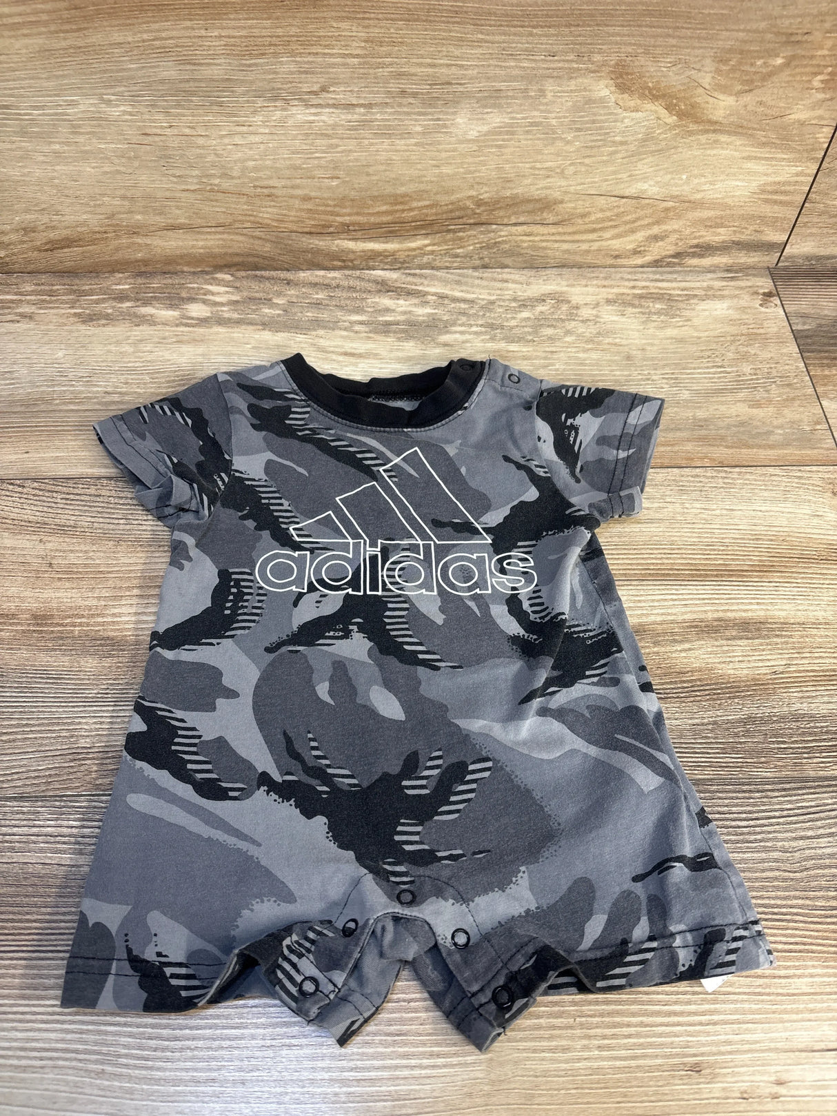 Gray camo baby romper with Adidas logo on wood background, short sleeve infant clothing