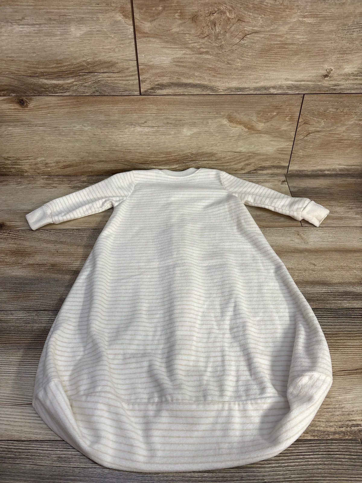 Front view of Carter’s blanket sleep sack showcasing ivory fabric, long sleeves, and rounded bottom on a wood floor