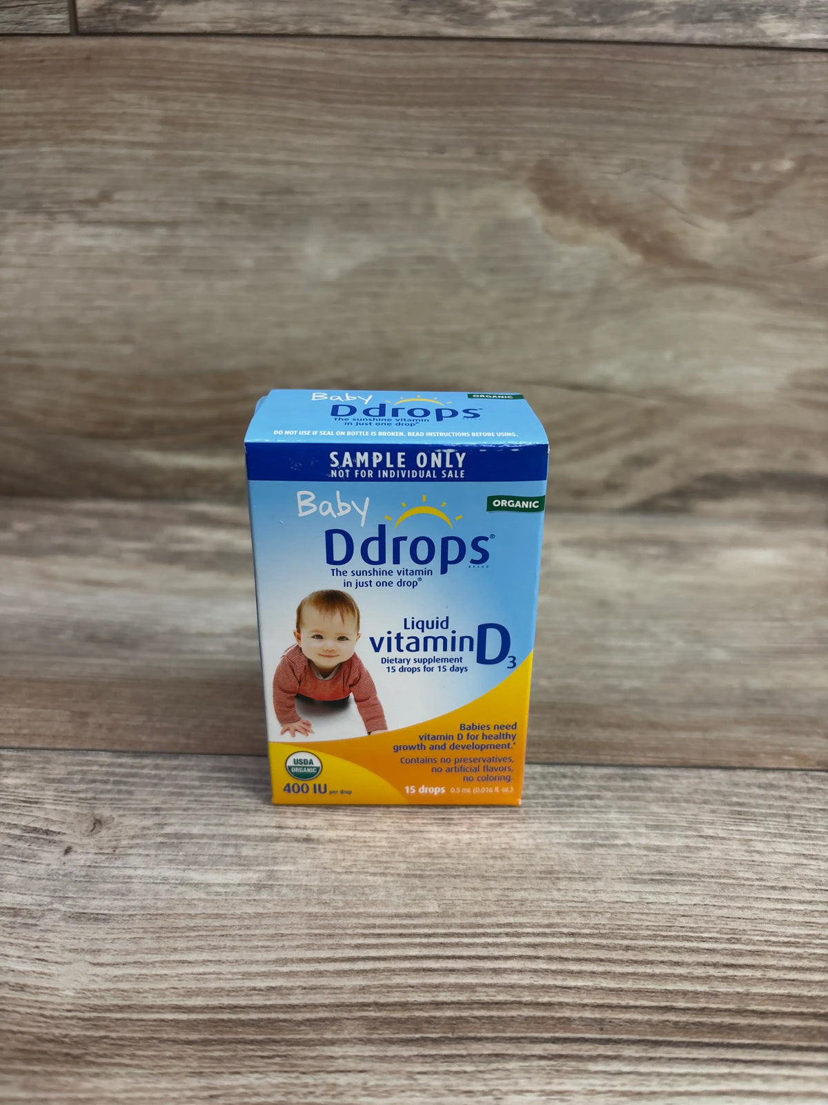 Front view of Baby Ddrops organic liquid vitamin D3 box showing 400 IU and 15 drops on a wood-grain surface