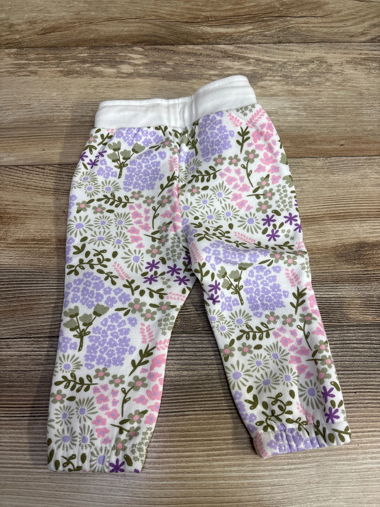 Baby leggings with pink, purple, and green floral pattern on wooden surface