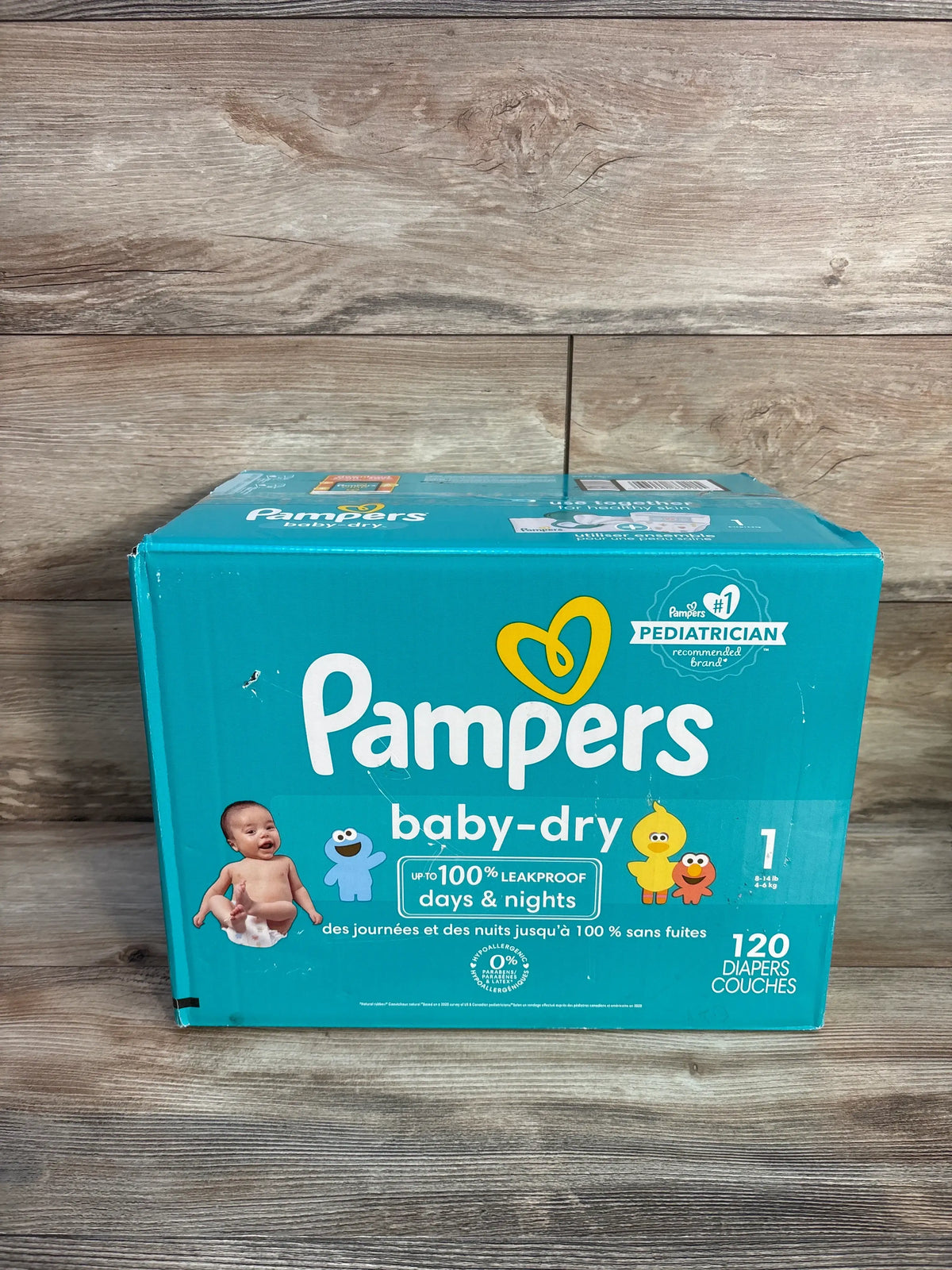 Front view of NEW Pampers Baby Dry Diapers 120ct Size 1 box showcasing 120 diapers and up to 100% leakproof protection on a wood floor