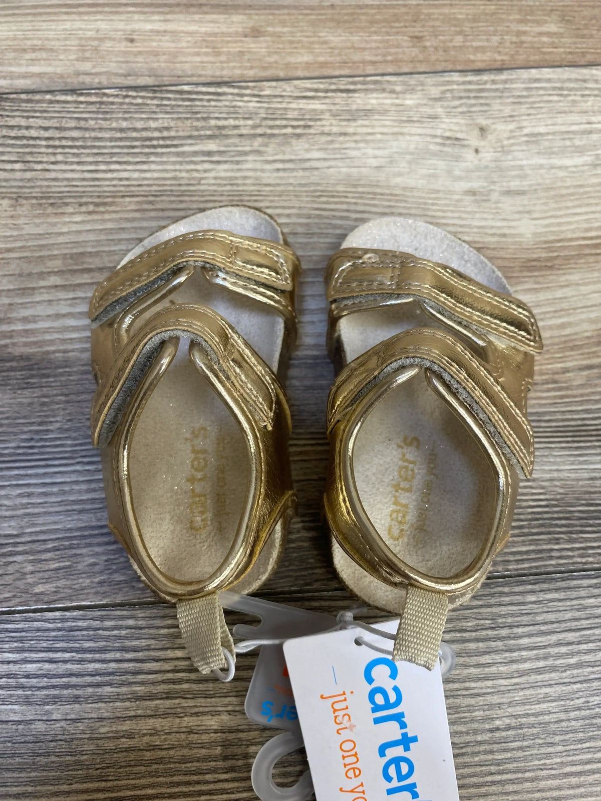 Gold baby sandals with velcro straps, Carter's brand, on wooden floor