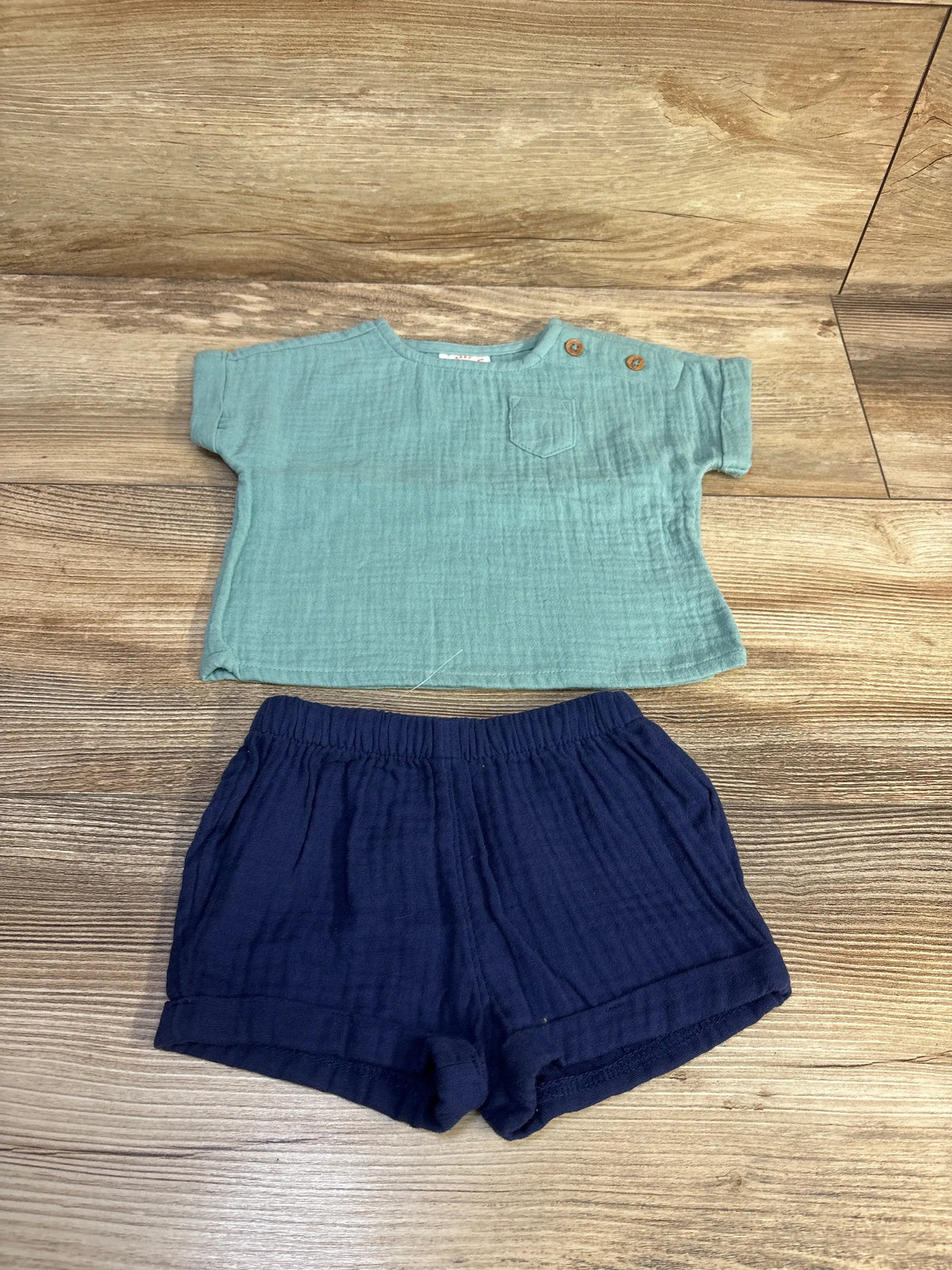 Flat lay of Cat & Jack blue gauze shirt and shorts set with chest pocket and elastic waist on wood surface