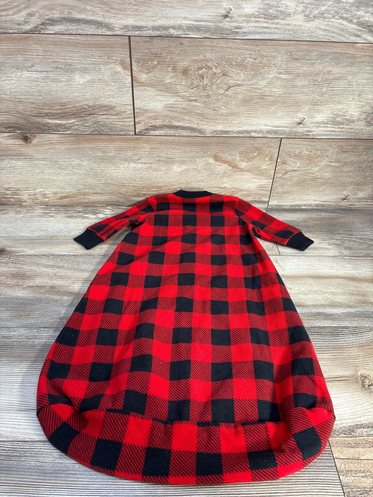 Front view of Carters red plaid blanket sleep sack for 3-6 months with long sleeves and black cuffs on a wood-look floor