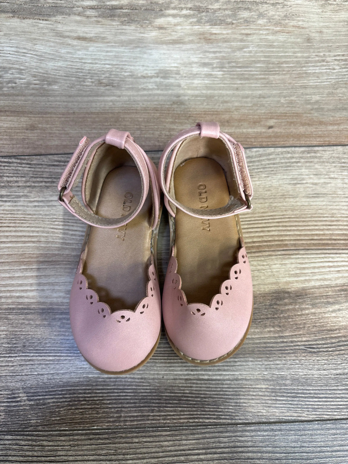 Pink Old Navy chunky eyelet-trim ballet flats for kids, size 5c, on a wooden surface.