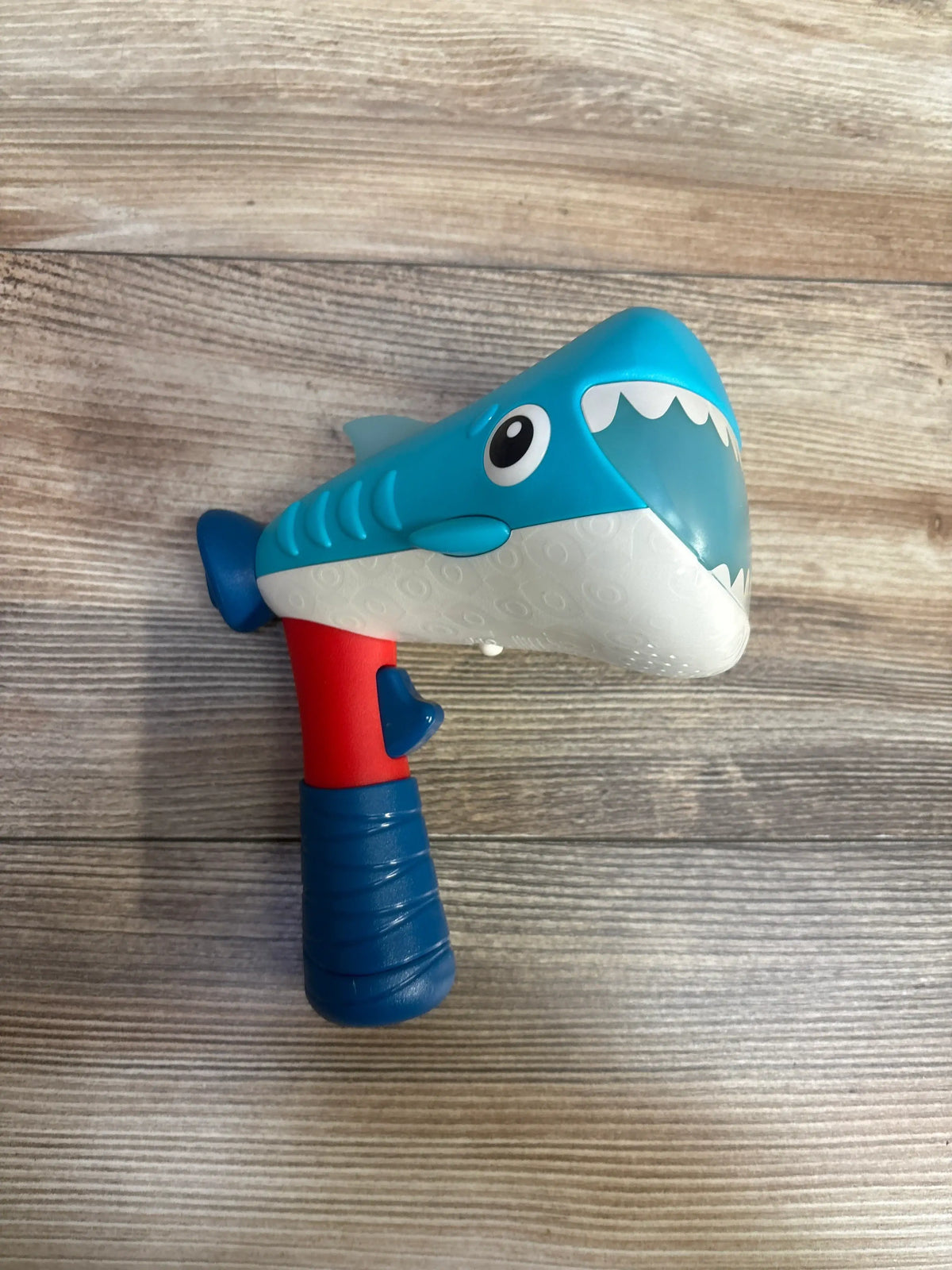 Side view of B. Toys Silly Speaker Voice Changing Megaphone showcasing shark design with a wood-look background