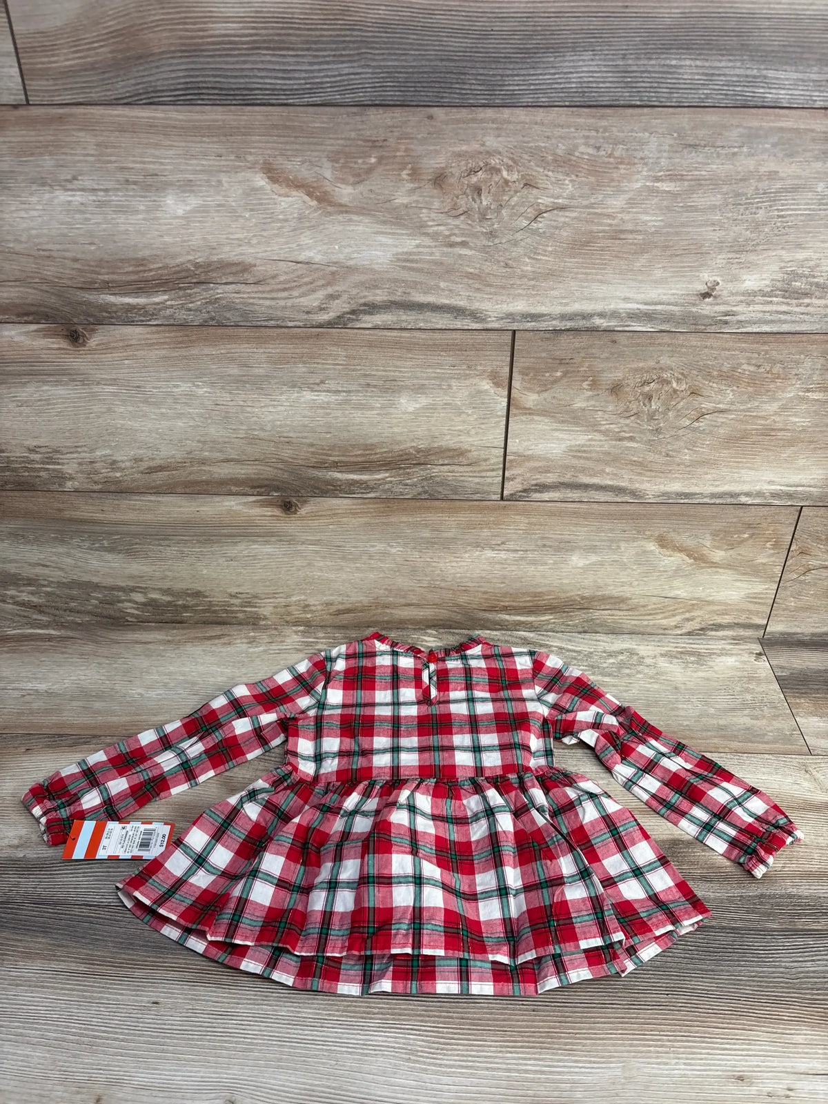 Red and white plaid long sleeve toddler dress with tag on wood background