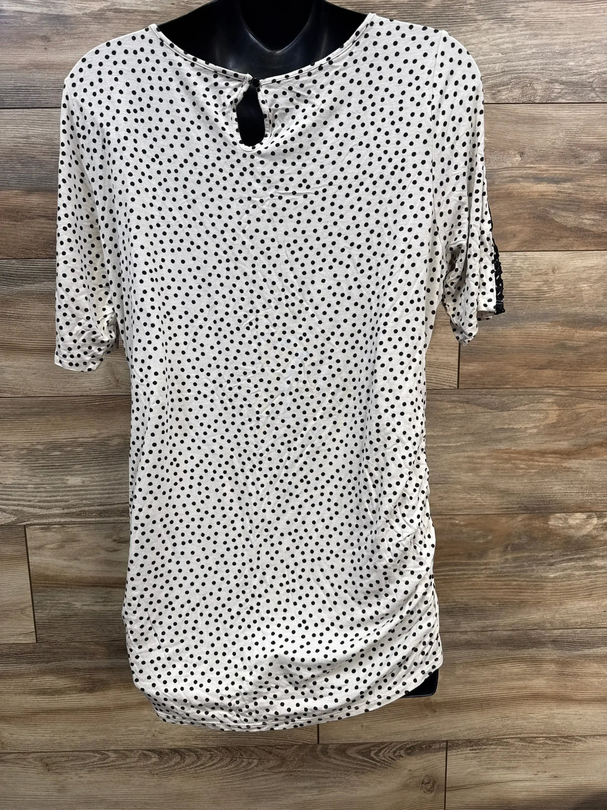 White polka dot short sleeve blouse with keyhole back, displayed on wood background