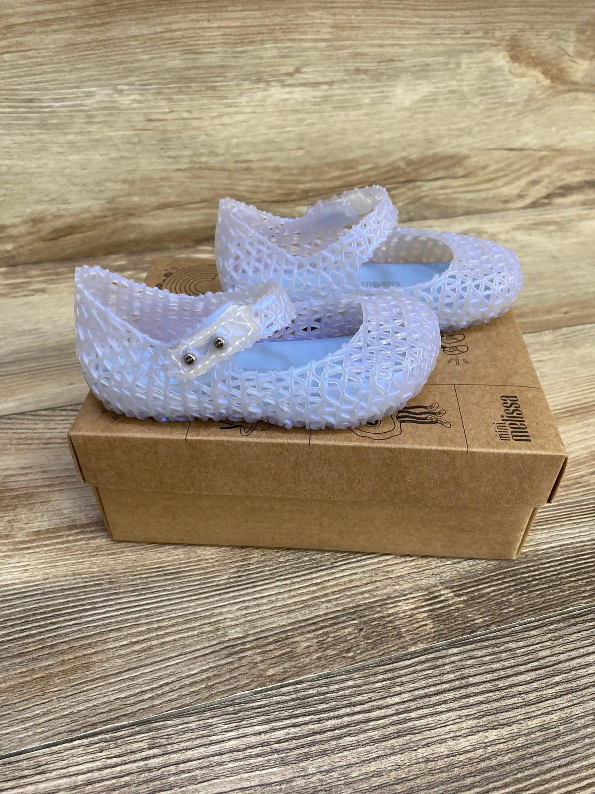 Three-quarter view of NEW Mini Melissa Campana Papel jelly flats sz 7c showcasing pearly blue woven mesh straps on Mini Melissa box on wood