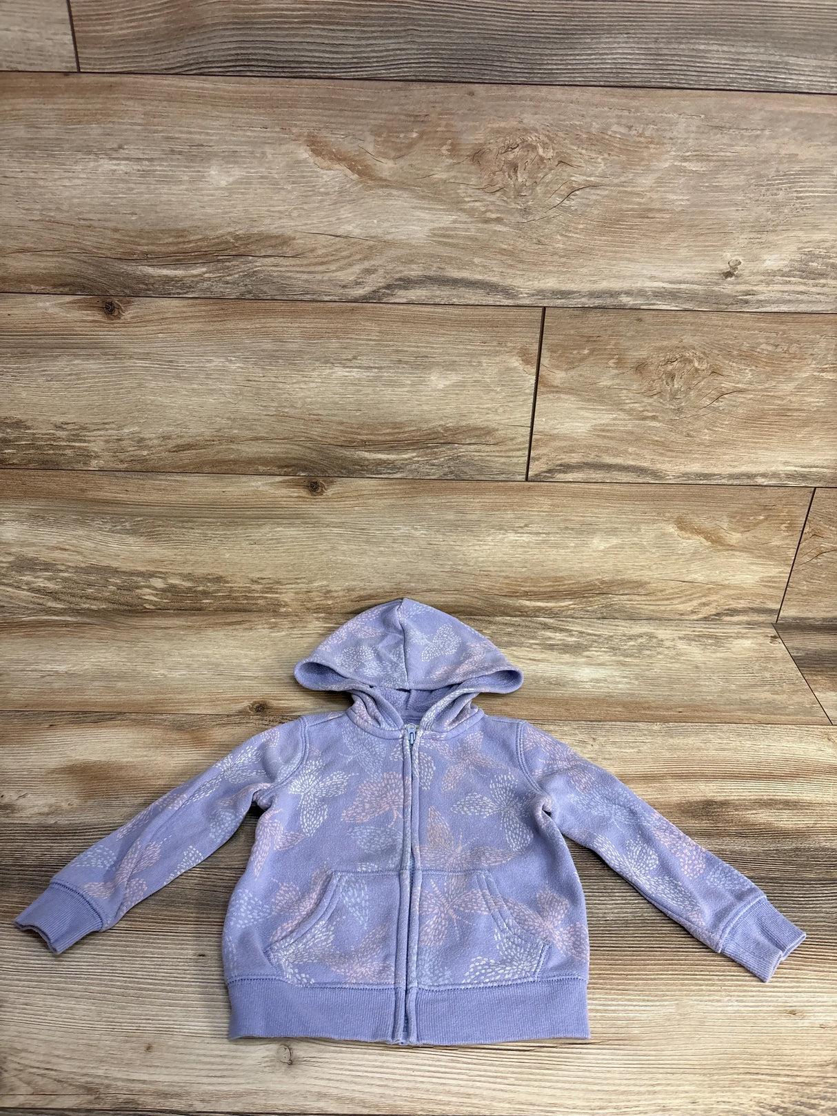 Lilac kids zip-up hoodie with hood and leaf pattern on wooden floor background