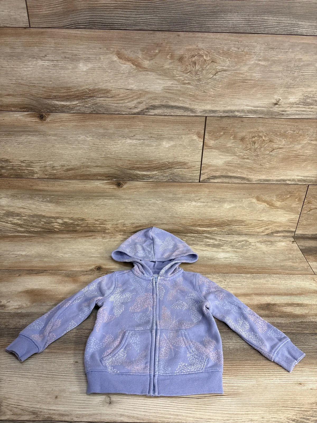 Lilac kids zip-up hoodie with hood and leaf pattern on wooden floor background