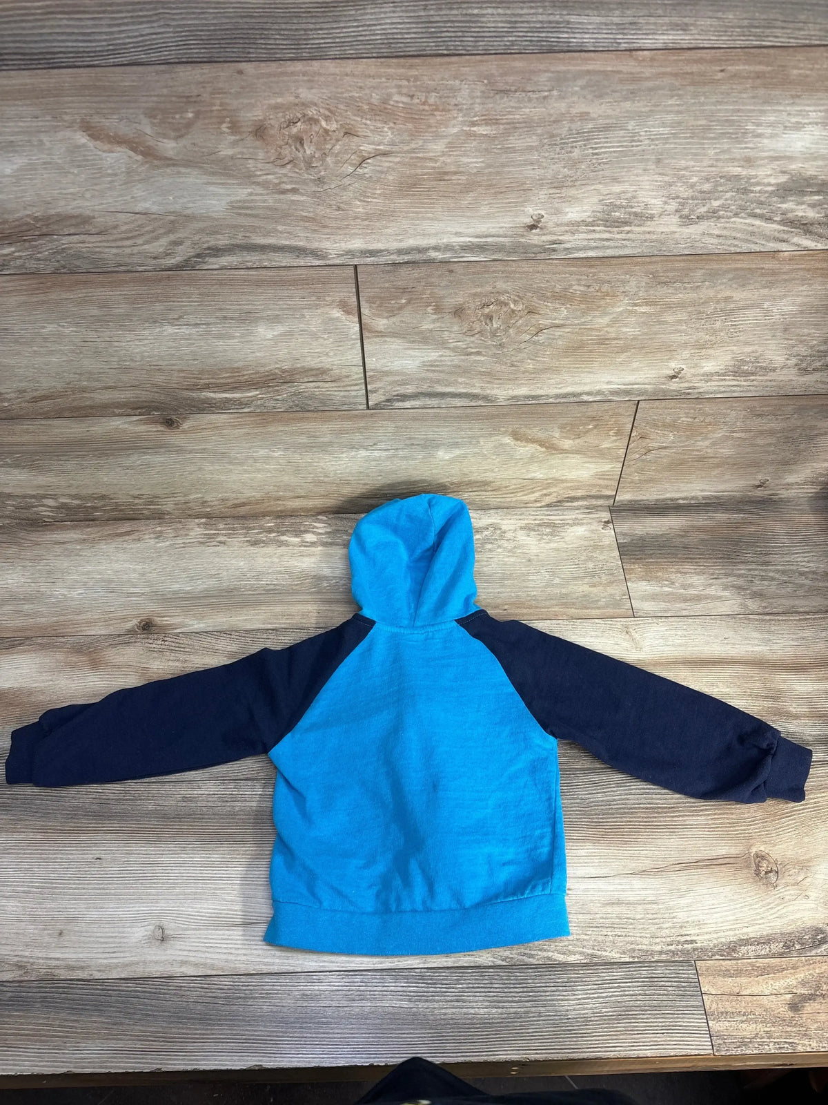 Back view of Phat Farm 4T full-zip toddler hoodie showcasing bright blue body with navy raglan sleeves and hood on wood floor