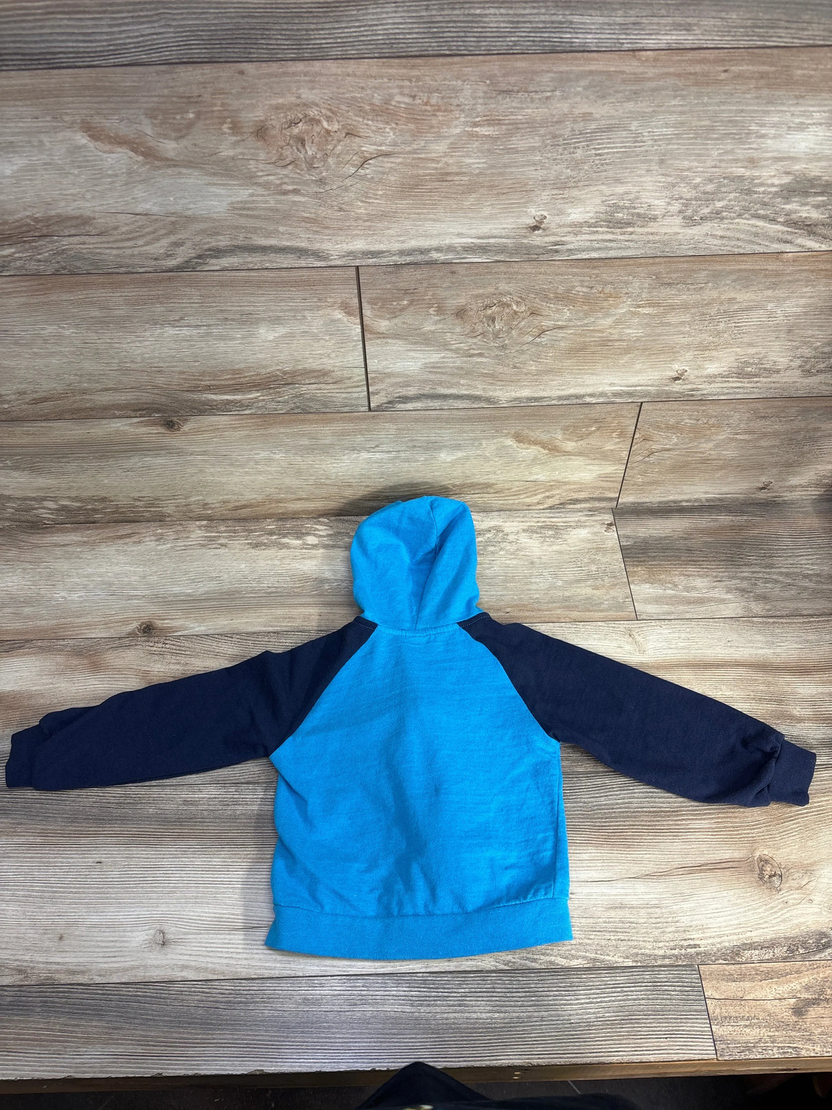 Blue and navy toddler hoodie displayed on wood floor