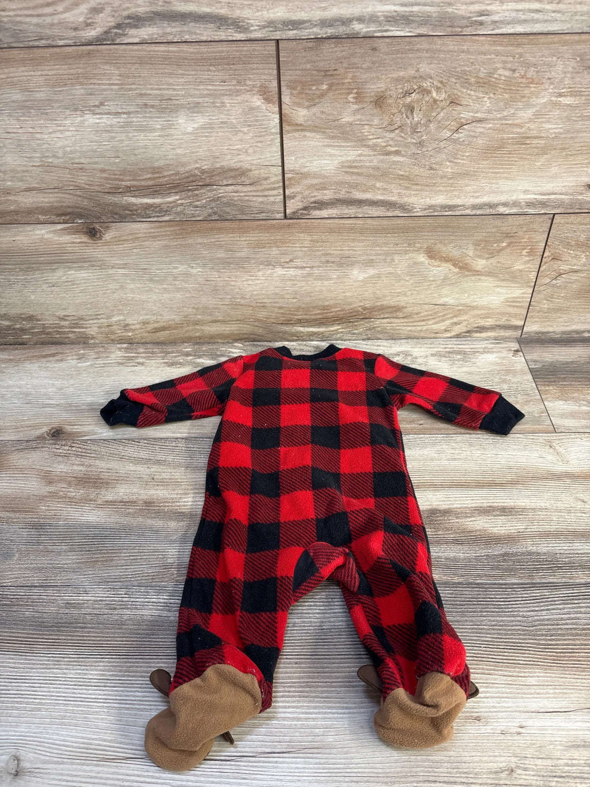 Back view of Carter's red and black buffalo plaid sleeper showing footed tan soles and black cuffs on wood background