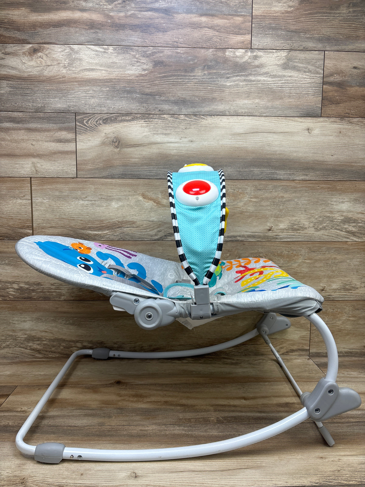 Side view of Baby Einstein Ocean Explorers Opus rocker showing ocean-themed seat on wood flooring