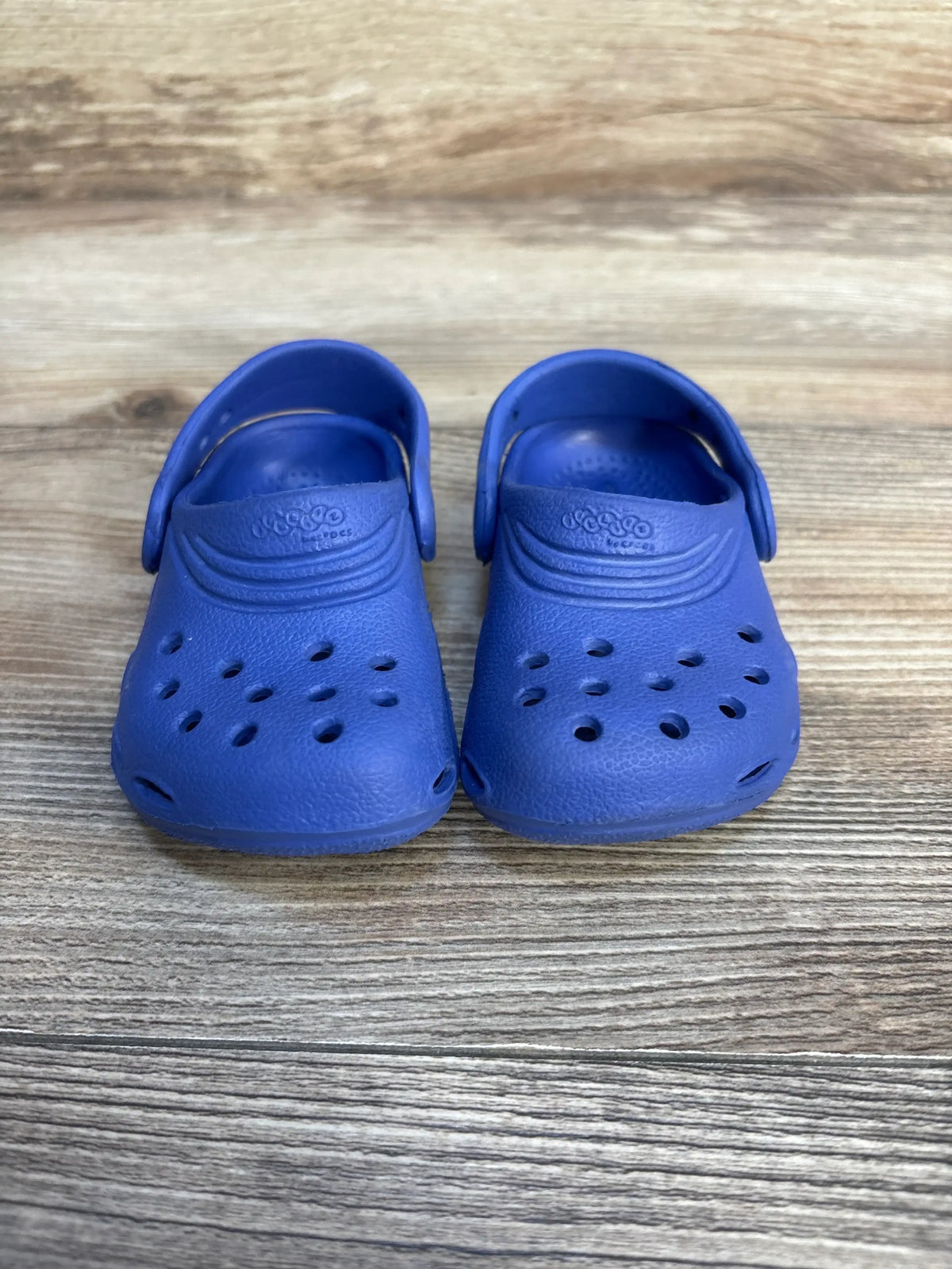 Front view of Crocs Classic Clog (toddler size 4/5 C) showing ventilation holes and back straps on wooden floor