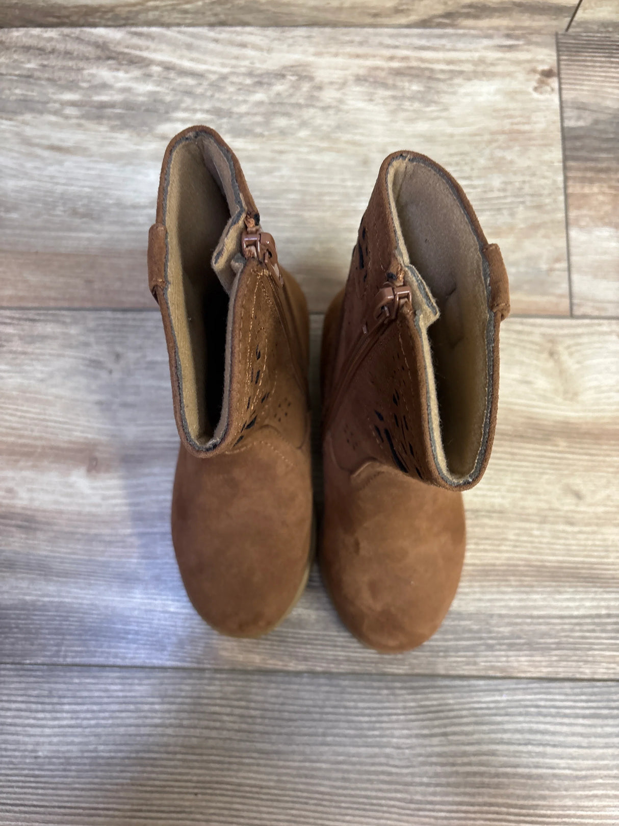 Top view of Lil’ Jayla toddler western boots in brown suede showing side zipper and cutout detail on wood-look floor